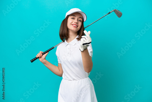 Young Ukrainian golfer player woman isolated on blue background making money gesture