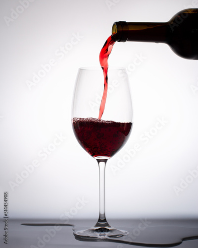 Red wine pouring into a glass from bottle isolated on white background