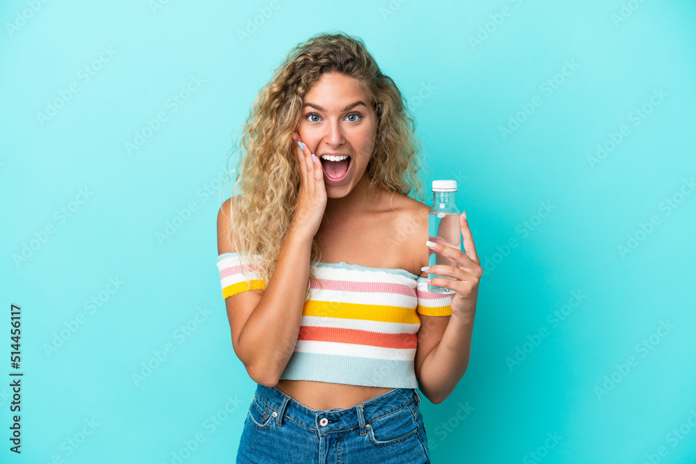 Young blonde woman with a bottle of water isolated on blue background with surprise and shocked facial expression Young blonde woman with a bottle of water isolated on blue background with surprise and shocked facial expression