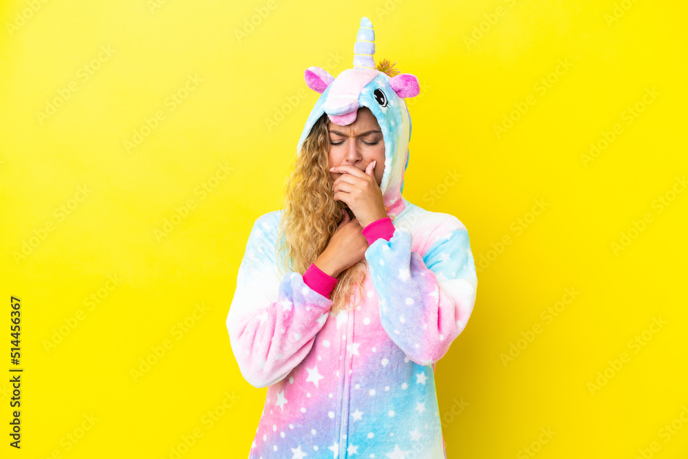 Girl with curly hair wearing a unicorn pajama isolated on yellow background is suffering with cough and feeling bad Girl with curly hair wearing a unicorn pajama isolated on yellow background is suffering with cough and feeling bad