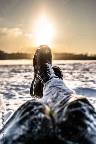 Snowy legs with boots in the winter. Sunset in the sky