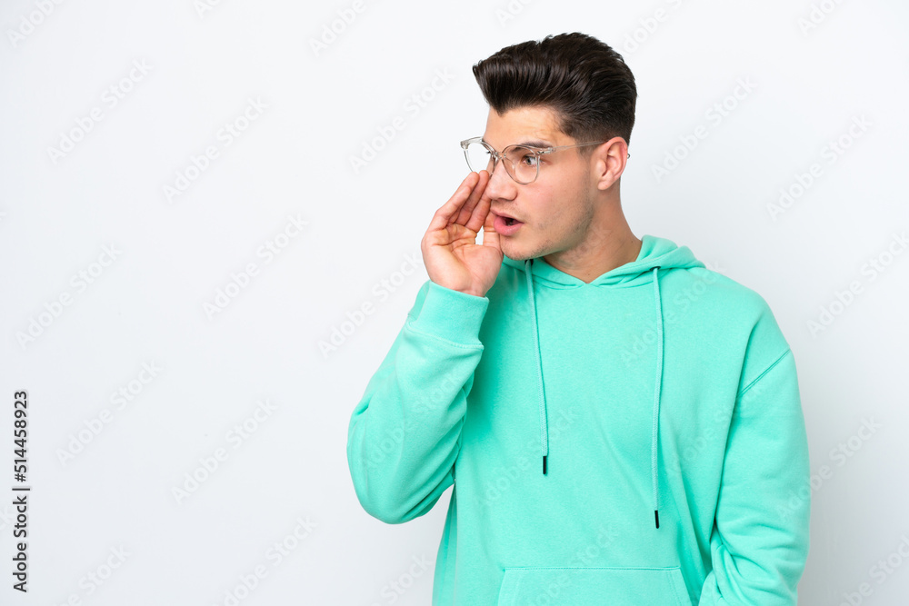 Young handsome caucasian man isolated on white bakcground whispering something with surprise gesture while looking to the side Young handsome caucasian man isolated on white bakcground whispering something with surprise gesture while looking to the side