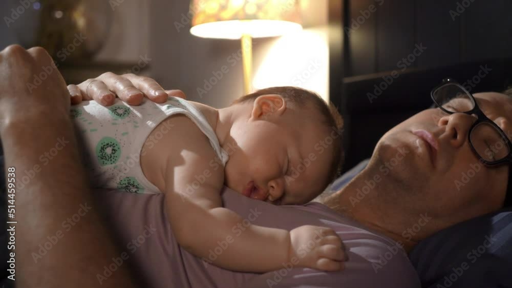 A tired father sleeping together with his baby son on his chest. Family ...