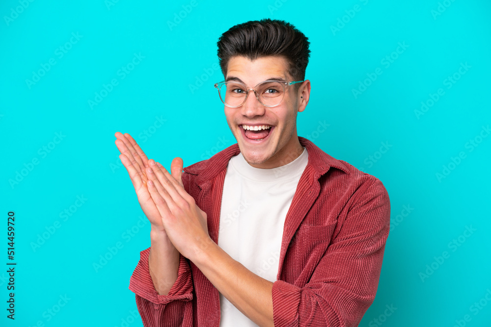Young handsome caucasian man isolated on blue bakcground With glasses and applauding Young handsome caucasian man isolated on blue bakcground With glasses and applauding