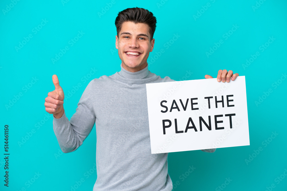 Young handsome caucasian man isolated on blue bakcground holding a placard with text Save the Planet with thumb up Young handsome caucasian man isolated on blue bakcground holding a placard with text Save the Planet with thumb up