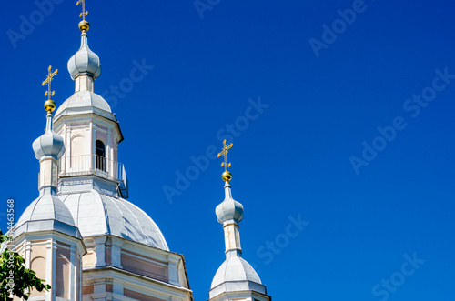 domes of a pink-and-white church with golden crosses against a bright blue sky on a sunny day photo