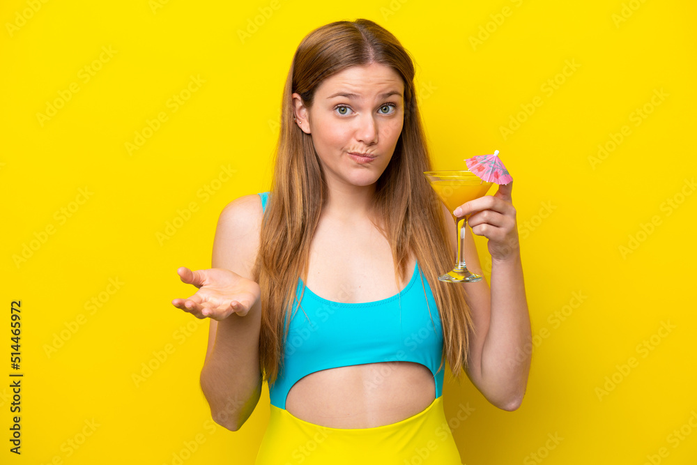 Young caucasian woman holding a cocktail isolated on yellow background making doubts gesture while lifting the shoulders