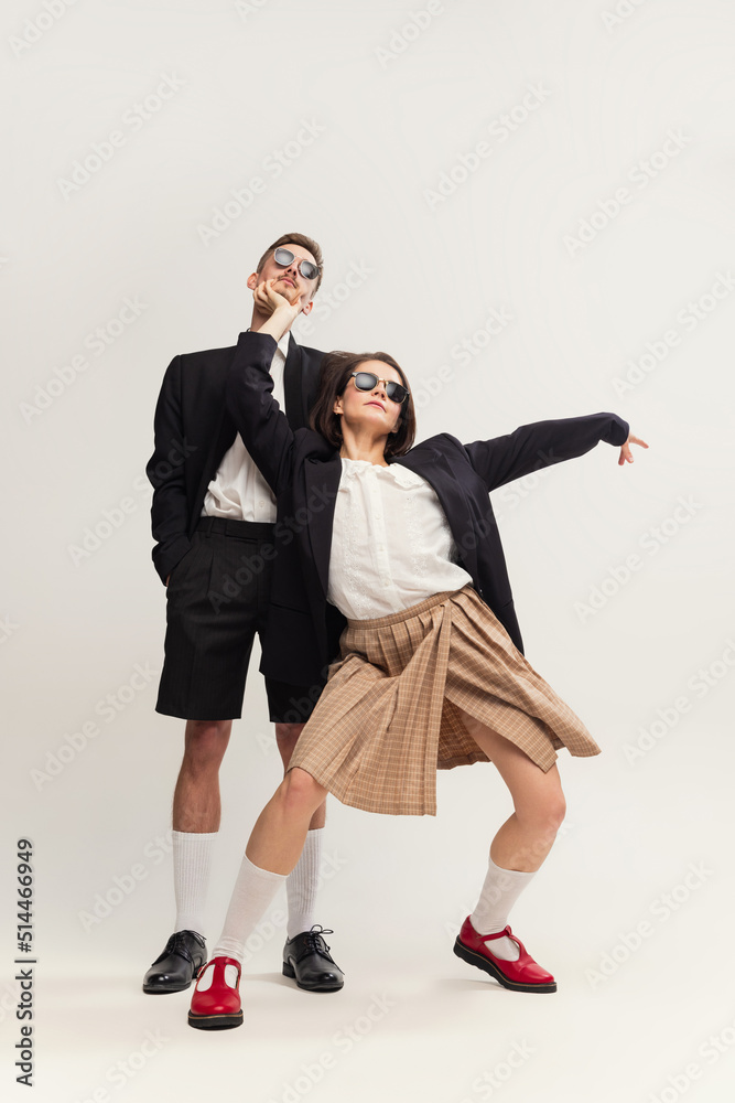 Full-length portrait of stylish young couple, man and woman in retro suit posing isolated over grey studio background. Party mood Full-length portrait of stylish young couple, man and woman in retro suit posing isolated over grey studio background. Party mood
