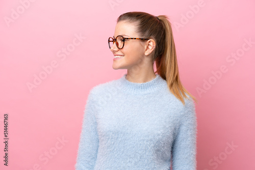 Young caucasian woman isolated on pink background looking side