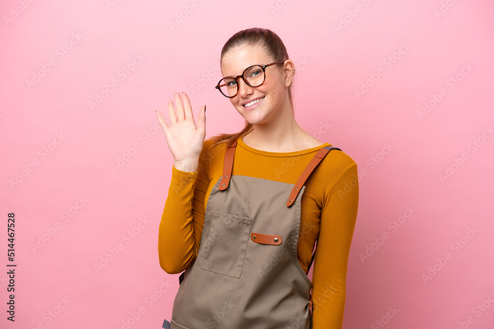 Woman with apron isolated on pink background saluting with hand with happy expression Woman with apron isolated on pink background saluting with hand with happy expression