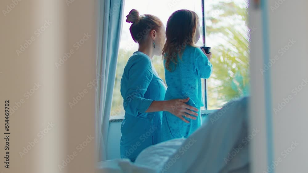 Morning at the bedroom. Mother and kid enjoy early morning time together and watch in the window