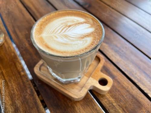 beautiful cup of cappuccino coffee with latte art in the wooden space background photo