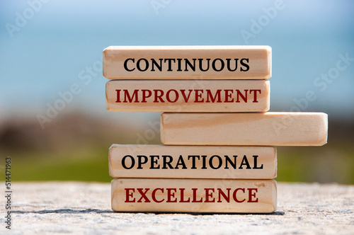 Continuous improvement Operational excellence text on wooden blocks with blurred nature background.