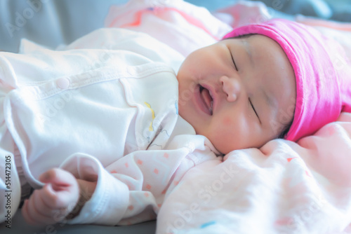 Blur images of Asian baby newborn girl is 7-day-old, is sleeping and smile on the bed, to family and newborn concept.