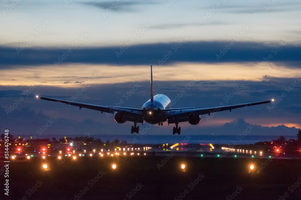 Airplane landing on runway with colour sky