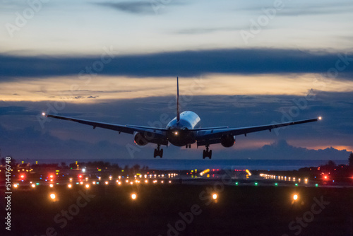 Airplane landing on runway with colour sky