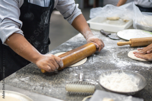 Male baker prepares bread. Male baker sprinkle the dough with flour. 