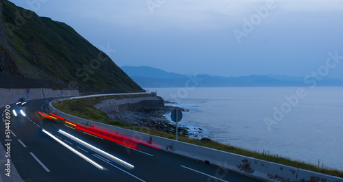Car lights on the road at dusk by the sea, Euskadi photo