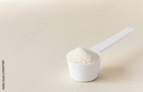 A scoop with hydrolyzed collagen powder on a beige background. The concept of food additives, healthy. Copy space photo