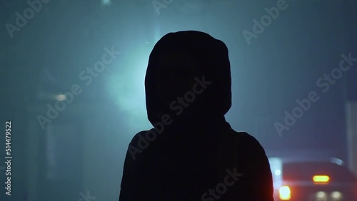 Silhouette of a young man dressed in a hood in the backlight.