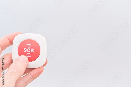 person holding a red SOS button against white background - emergency and danger situation concept