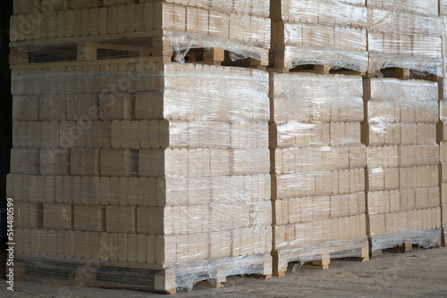 Pressed pine wood briquettes on pallets. Solid fuel for stoves from softwood shavings.
