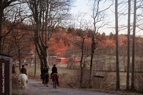 a group of teenagers on a horseback ride together at sunset through a village dirt road