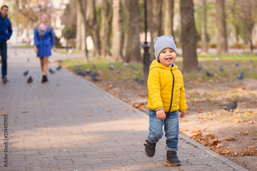 A little boy runs along the path in the park.