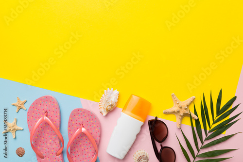 Summer vacation accessories, sunglasses, flip-flops, sunscreen colored background. Traveling essentials flat lay with copy space