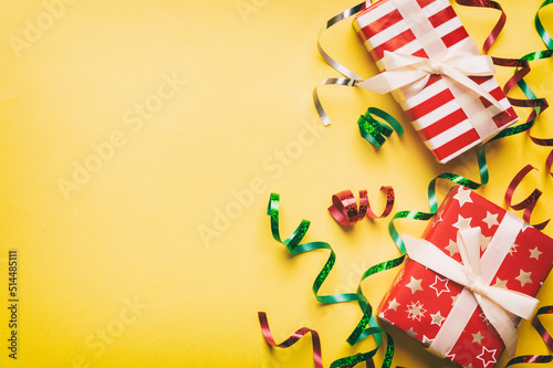 Holiday flat lay with gift boxes wrapped in colorful paper and tied decorated with confetti on colored background. Christmas, Birthday, Valentine and sale concept, top view