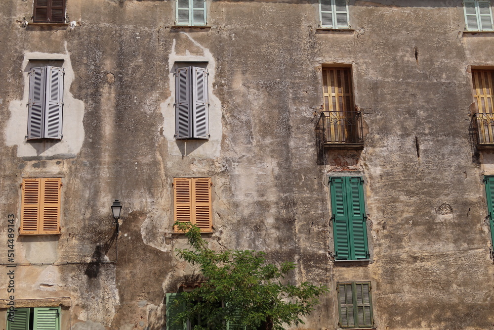 Obraz premium House, windows with shutters, balcony, bright colours against a washed stone wall, Corsica, France