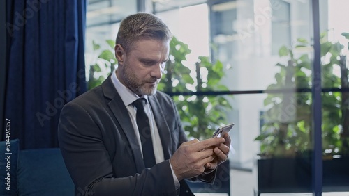 Serious businessman reading message on smartphone, thinking over information