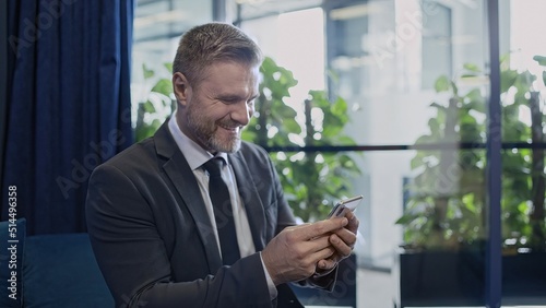 Successful businessman looking at smartphone, smiling happy with good news