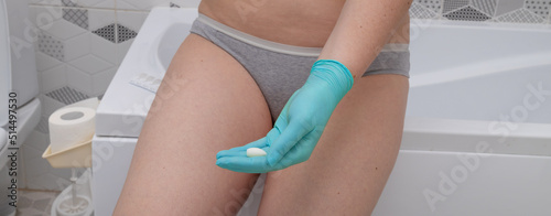 Concept of Gynecology, woman health. Woman in panties holds a Vaginal or rectal suppository against the backdrop of a bathroom. Concept of Gynecology, woman health. photo