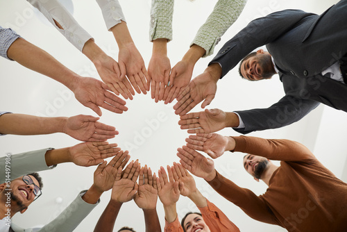 Fotografie Closeup downward view of diverse international people join hands in circle motivated for shared business result