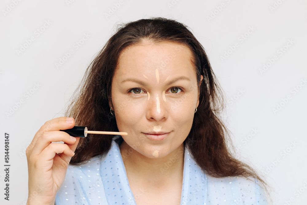 The girl applies concealer light corrector on the face, in the corners of the eyes. The girl applies concealer light corrector on the face, in the corners of the eyes.