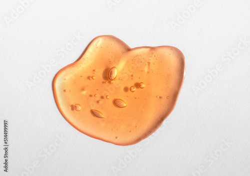 Orange cosmetics gel, serum or peeling drop on white background. Colorful warm yellow slime with air bubbles in the sunlight. High contrast trendy photo. Health protection and self-care concept