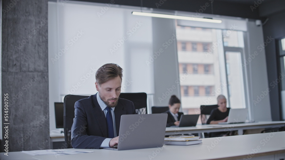 Male office worker typing on laptop, sitting in business office, working on a project Male office worker typing on laptop, sitting in business office, working on a project