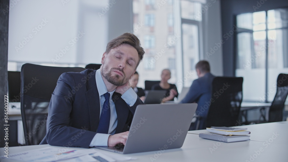 Sleepy male manager sitting at workplace in business office, tired of overworking Sleepy male manager sitting at workplace in business office, tired of overworking