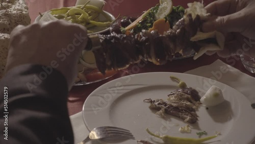 A man who tastes the horizontally cooked kebab typical of Turkish food culture and the products served with it at the dinner table.