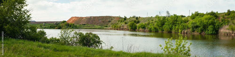 rich green grass on the shore of the lake. Panorama view of the river