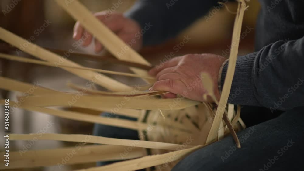 male worker weaving wicker baskets in the workshop where handmade wicker baskets are produced