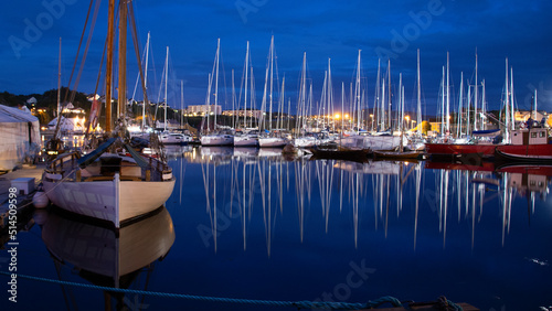 Photos Sailboats in port on a windless night. Reflections in water.