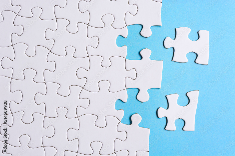 White jigsaw puzzle with some missing pieces on blue background. Copy space. White jigsaw puzzle with some missing pieces on blue background. Copy space.