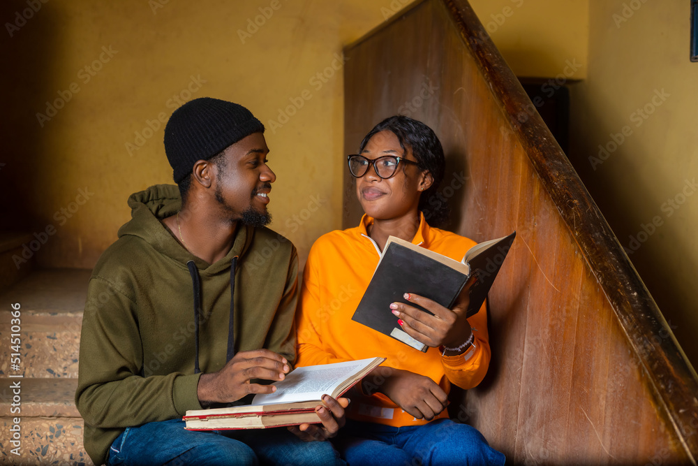 Obraz premium Smiling African male and female college student friends discussing about their books