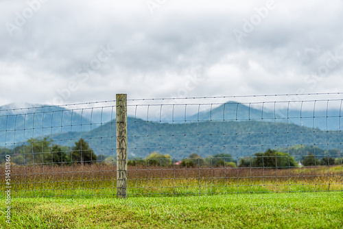 Buena Vista, Virginia countryside rural USA green grass field meadow near Blue Ridge parkway mountains with fence in foreground and clouds mist fog covering peak photo