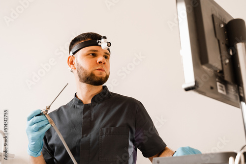 ENT doctor otolaryngologist with endoscope in hands. Prepearing for endoscopy procedure. Doctor with headlight. photo