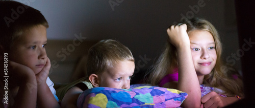 Three children of different ages watching movie before going to bed at night