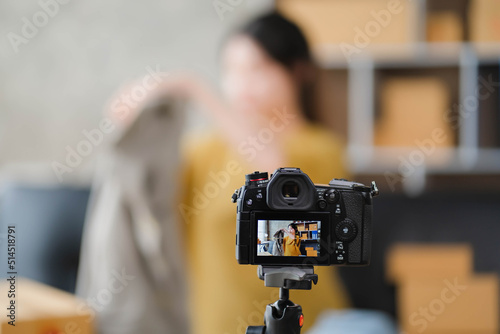 Young Asian women blogger showing clothes in front of the camera to recording vlog video live streaming at her shop. Network technology Business online influencer on social media concept