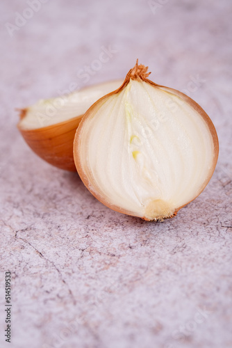 A halved onion on a white stone surface background.